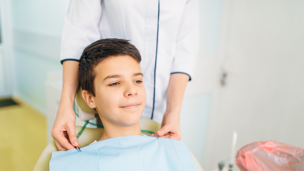 An adolescent patient appears at ease during a dental exam.